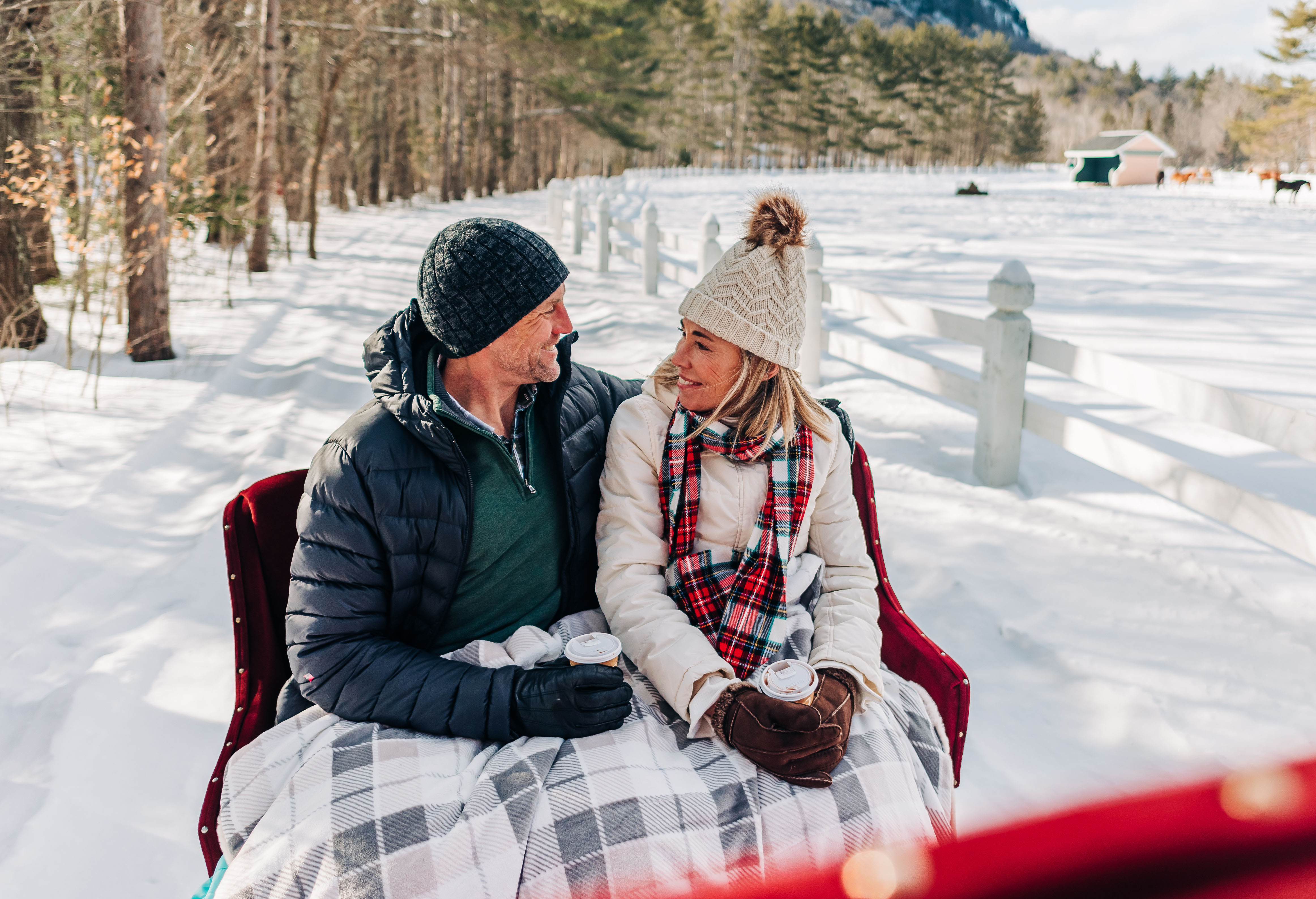 a couple with cups of cocoa on a sleigh ride