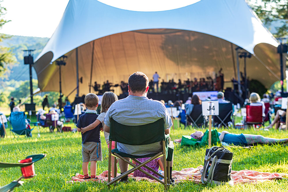 People sitting on a lawn in front of a tent