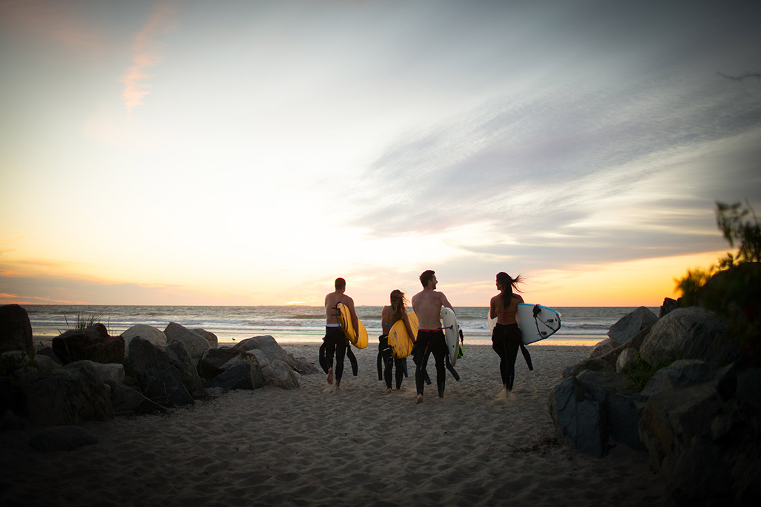 Surfers walking towards ocean at sunrise