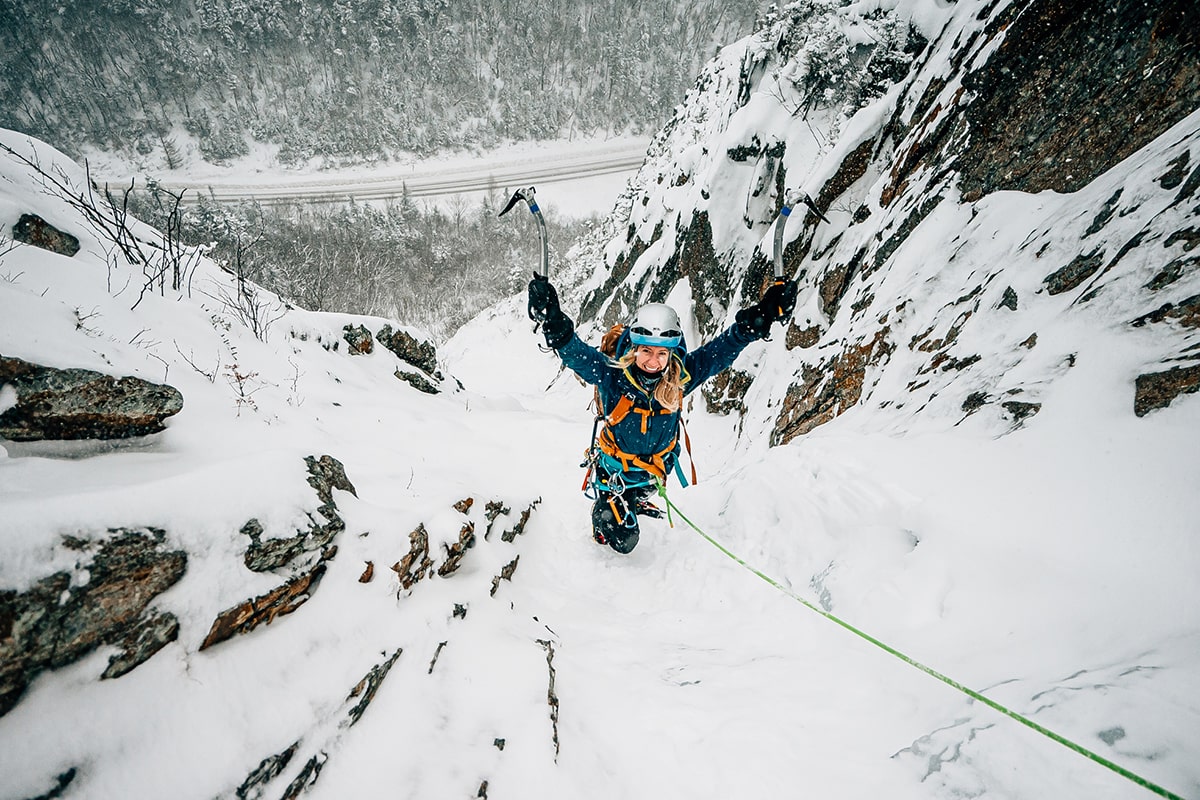 woman smiling hiking up a snowy mountain